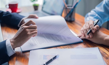 Management System Detail of a man's hands leafing through a stack of documents while sitting at a desk