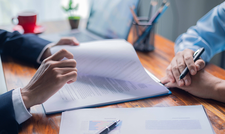 Management system Detail of a man's hands leafing through a stack of documents while sitting at a desk